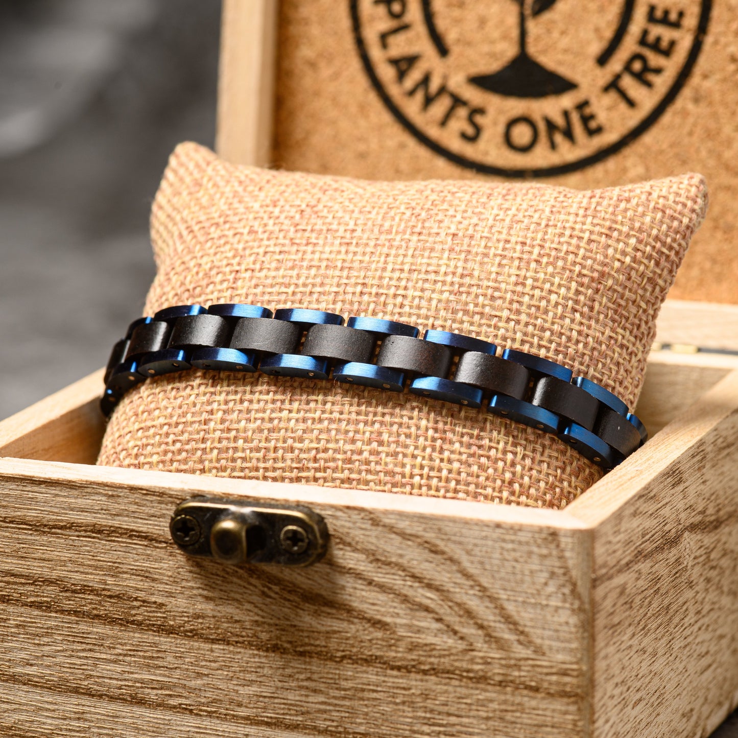 A close up shot of a sandalwood and blue steel bracelet in the watch box resting on a backdrop of stone