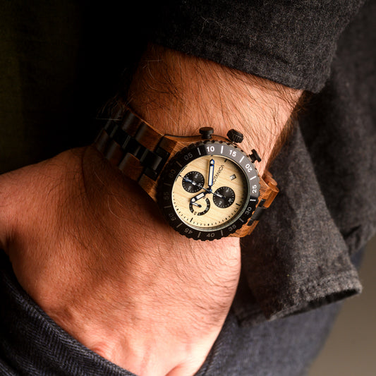Wooden wristwatch with a detailed face on a person's wrist, wearing a dark jacket.
