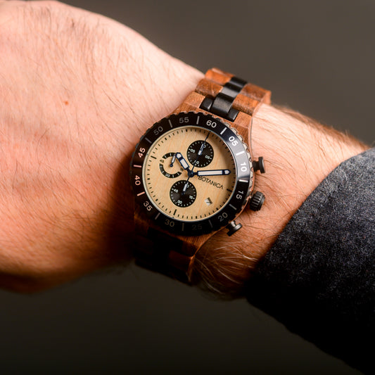 Wooden wristwatch with a detailed face on a wrist against a dark background