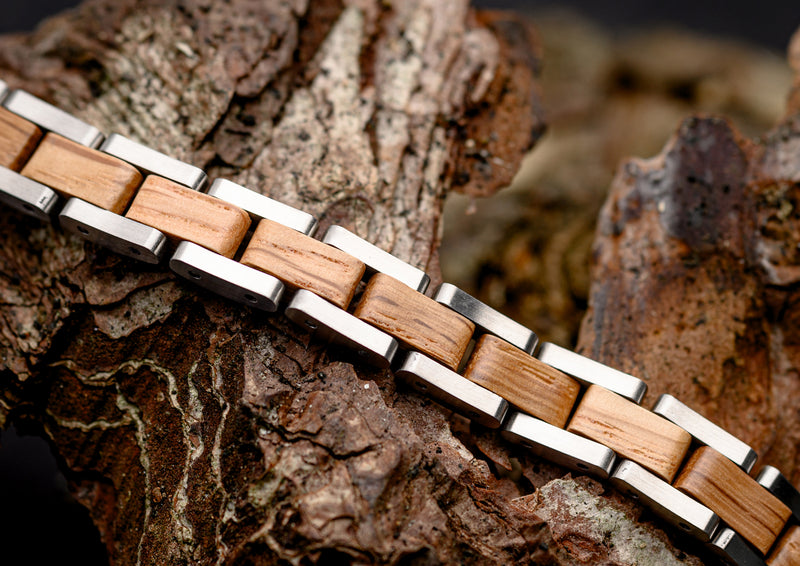 Wooden bracelet with metal accents on a textured wood surface