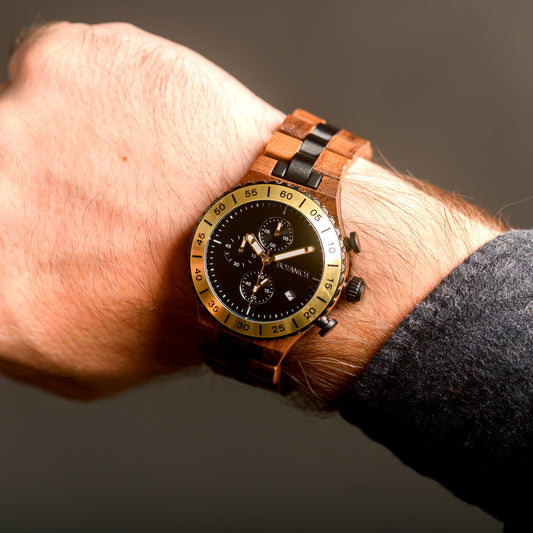 Wooden wristwatch with a black face on a wrist against a dark background