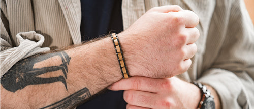 Close-up of a person's arm with tattoos wearing a wooden bracelet