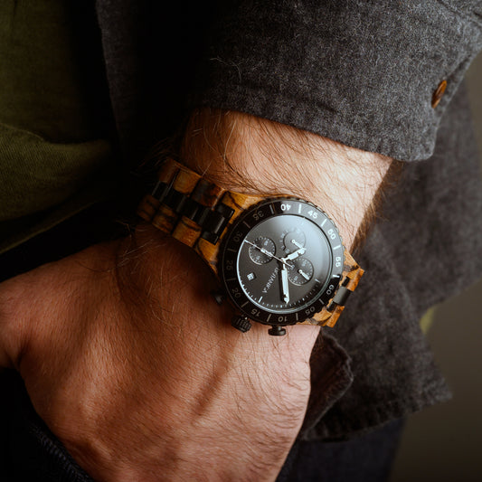 Wooden wristwatch on a person's wrist with a blurred background