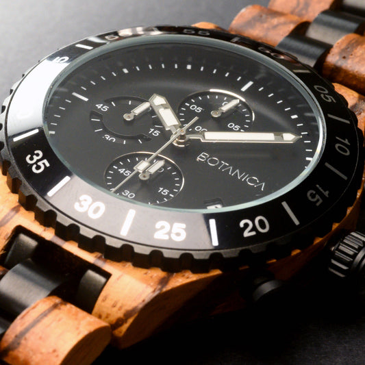 Close-up of a watch with a wooden strap and black dial on a dark background